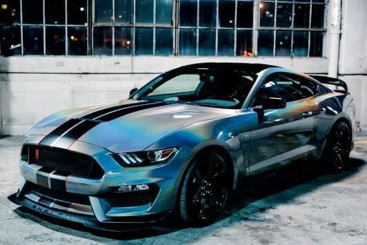 Ford Mustang fastback with black centre stripes, wrapped in Gloss Flip Psychedelic