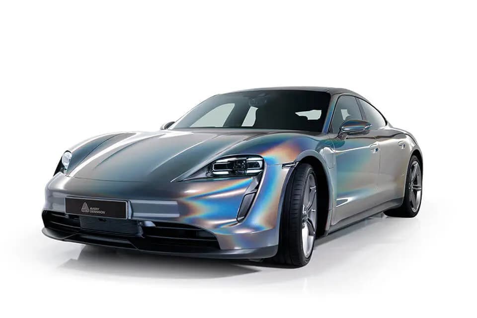 Avery Dennison studio image of a Porsche Taycan wrapped in Pride Prismatic Grey, a silver grey whose metallic flake catches iridescent light across the hood and front fender