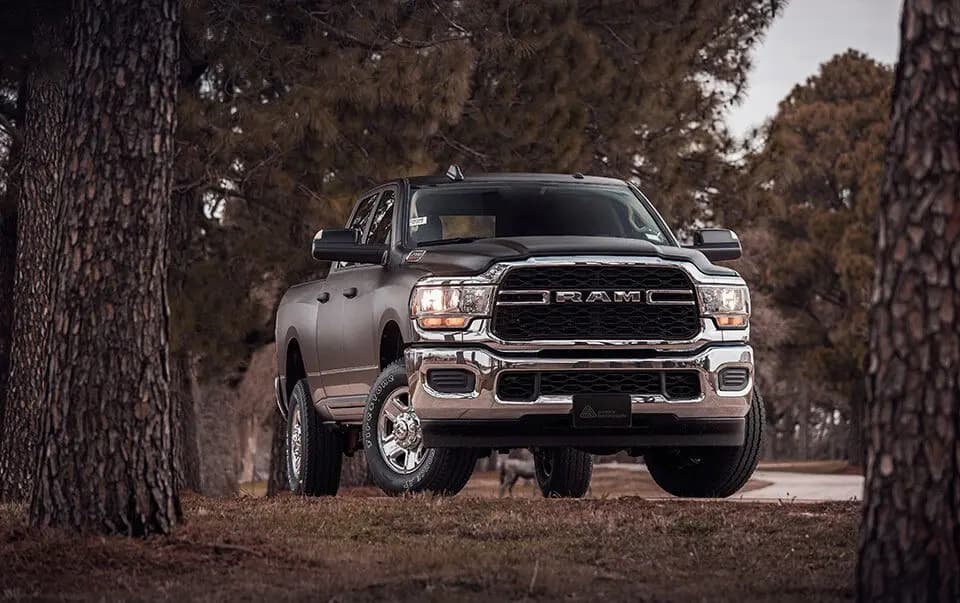 Ram crew cab pickup wrapped in Rugged Bedrock Grey, parked among pine trees