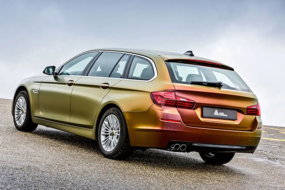 Rear three-quarter view of a BMW wagon on an Avery Dennison demonstration car, wrapped in ColorFlow Rising Sun and reading gold along the front doors and red across the tailgate