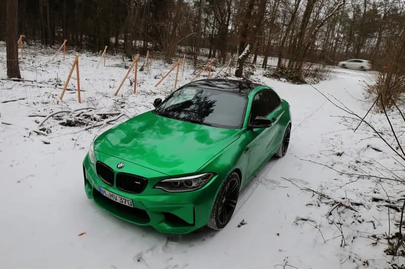 BMW coupe wrapped in Gloss Green Envy, parked on packed snow in front of a bare winter treeline