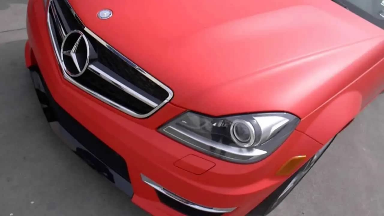 Close-up of a Mercedes-Benz front end wrapped in Matte Red, chrome grille and headlight left uncovered